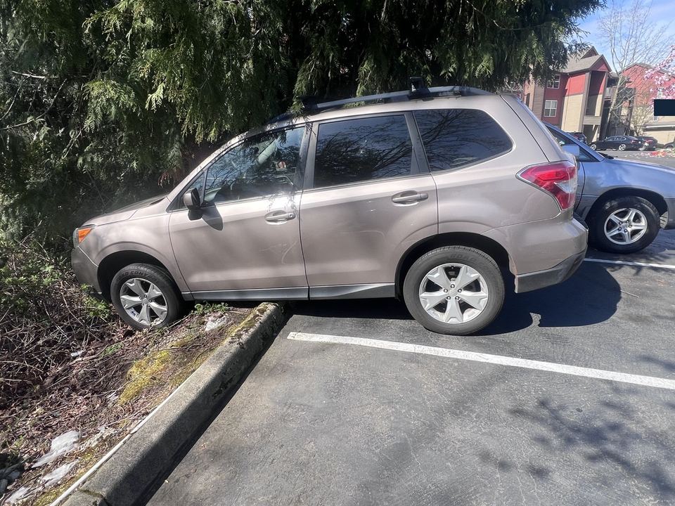 Subaru SUV with its front wheels beyond a parking-lot curb
