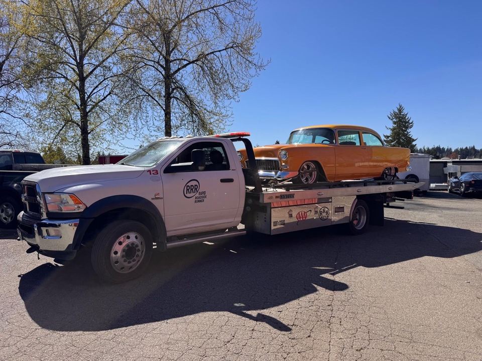 A Rapid Roadside Runner flatbed truck transporting an orange classic car
